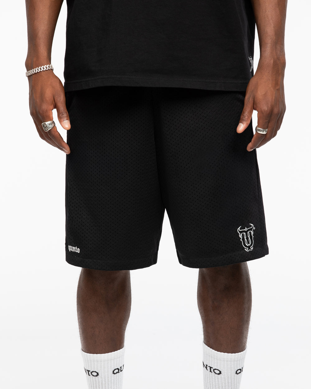 Person wearing black shorts with a logo on a white background