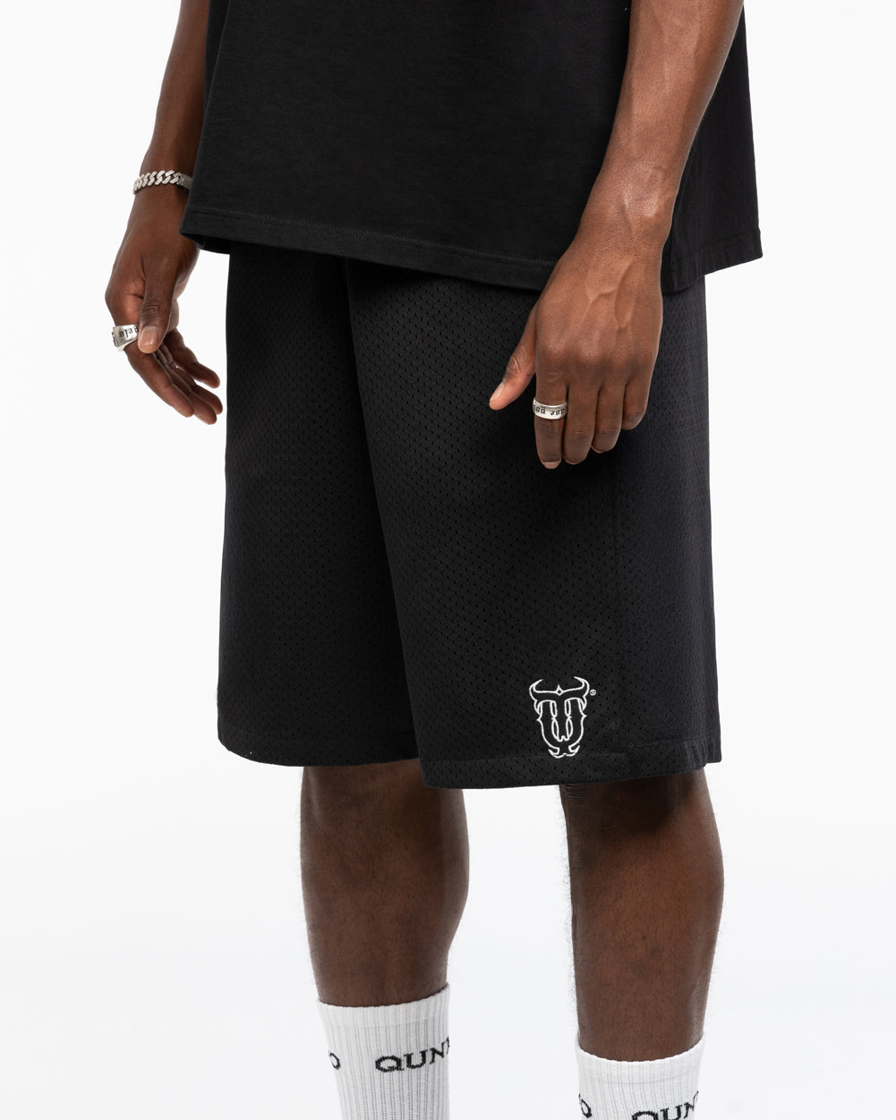 Person wearing black shorts with a logo on a white background