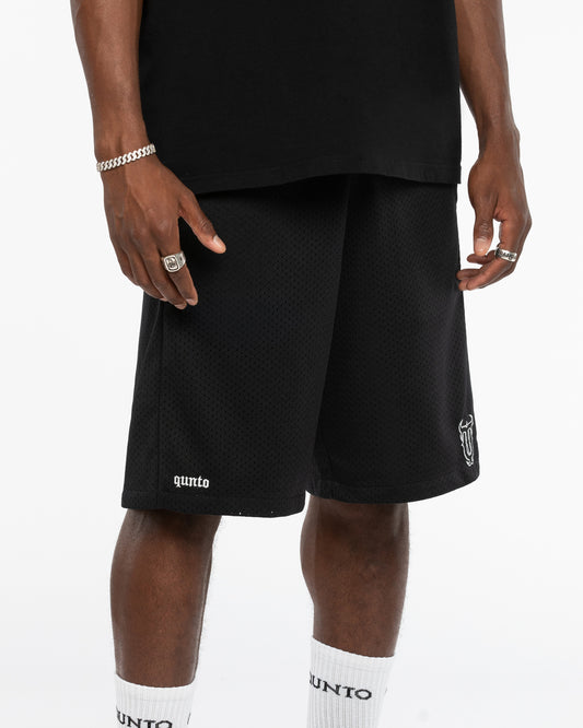 Person wearing black shorts with visible branding on a white background