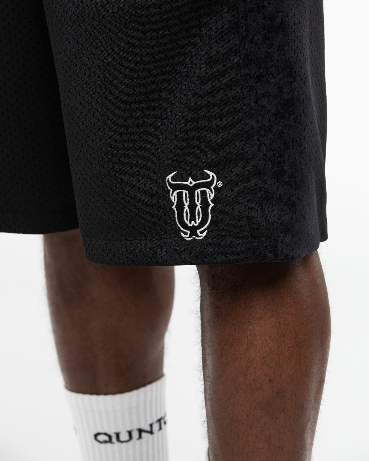 Black shorts with a white logo on a person wearing white socks.