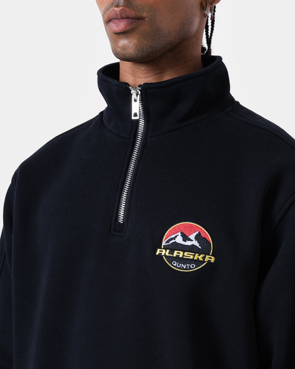 Model wearing ALASKA BADGE BLACK HALFZIP, a loose fit black half-zip sweatshirt with mountain logo.