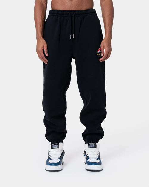 ALASKA BADGE BLACK JOGGER displayed on model, featuring loose fit, side and back pockets, elastic waistband.