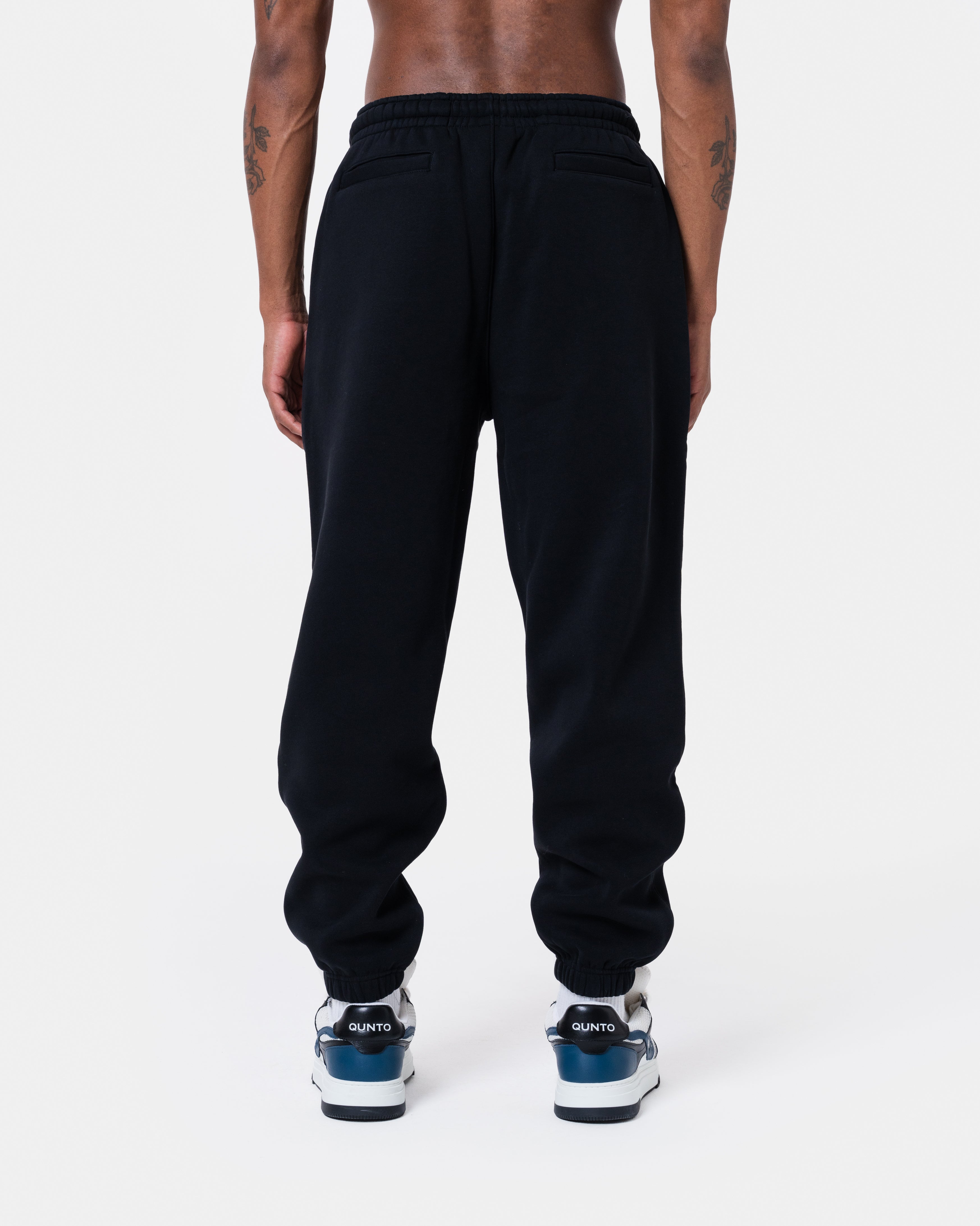 Man wearing ALASKA BADGE BLACK JOGGER with back pockets and elastic waistbands in black color.